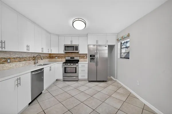 a kitchen with white cabinets and stainless steel appliances