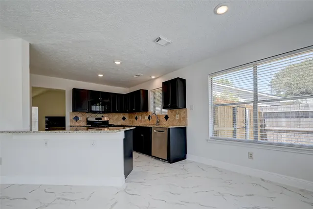 a kitchen with stainless steel appliances granite countertop a stove a sink and a refrigerator