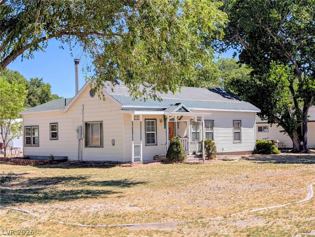 997 Phillips Street Panaca, NV 89042 - Photo 1 of 19 A charming cottage featuring a welcoming covered porch, nestled amongst mature trees, offering a tranquil setting.