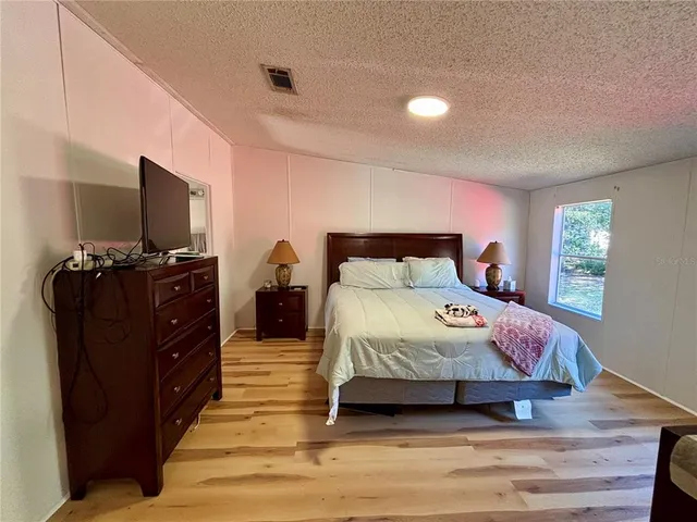 a bedroom with a bed and a flat tv screen on dresser