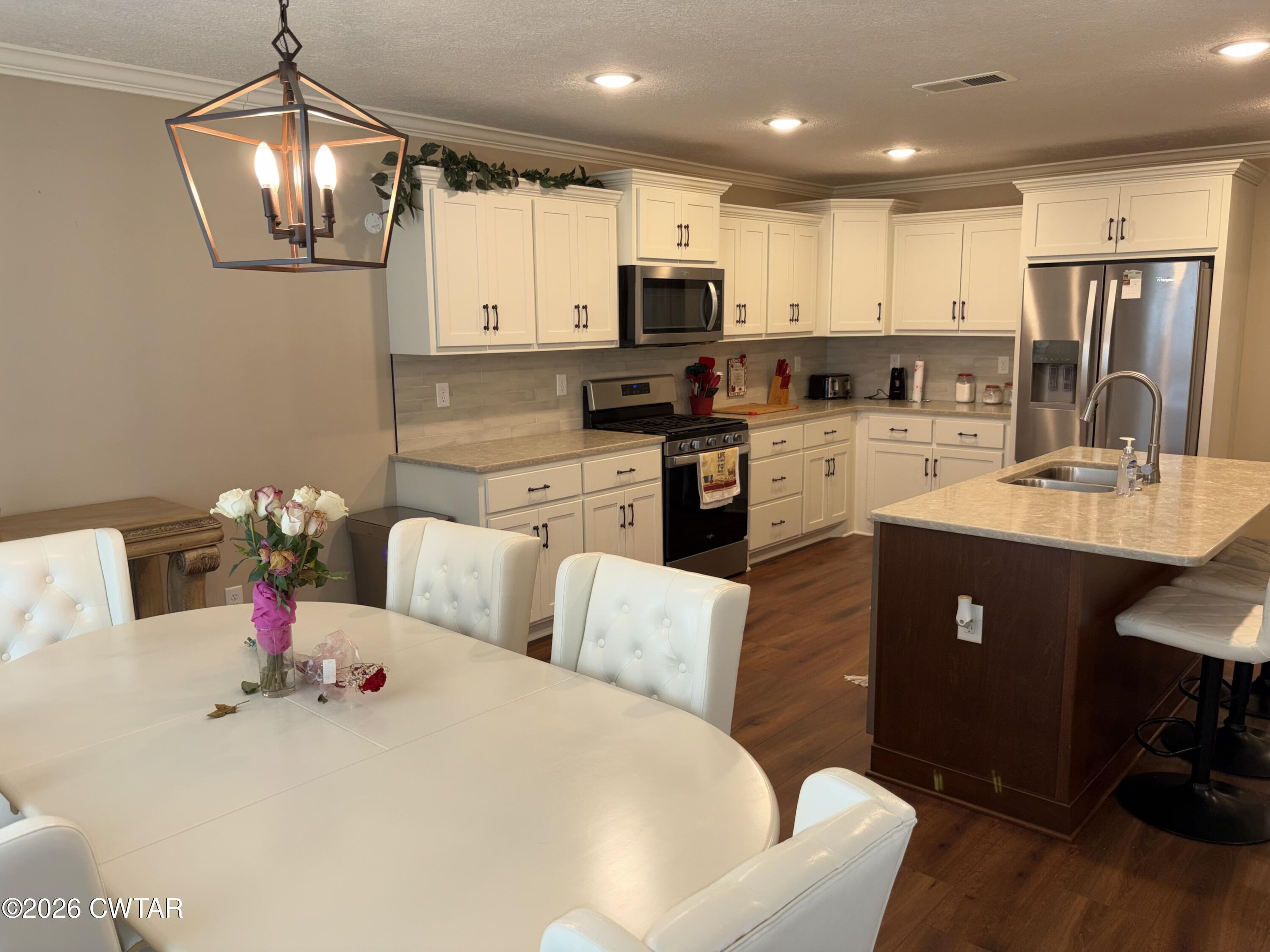 103 Gatewick Drive Jackson, TN 38305 - Photo 8 of 29 a kitchen with stainless steel appliances kitchen island granite countertop a refrigerator a sink dishwasher a dining table and chairs with wooden floor