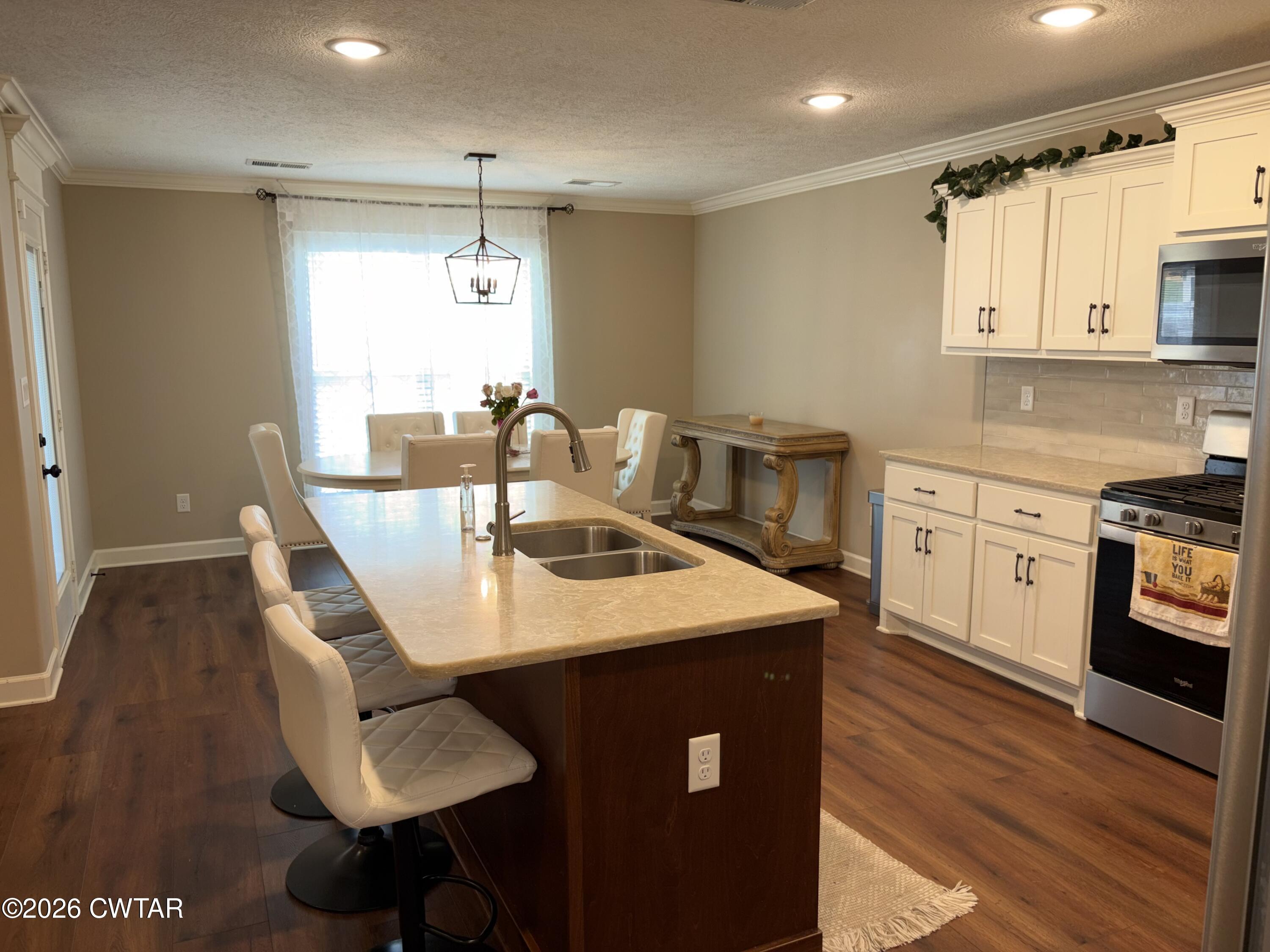 103 Gatewick Drive Jackson, TN 38305 - Photo 9 of 29 a kitchen with stainless steel appliances a kitchen island hardwood floor sink stove dining table and chairs