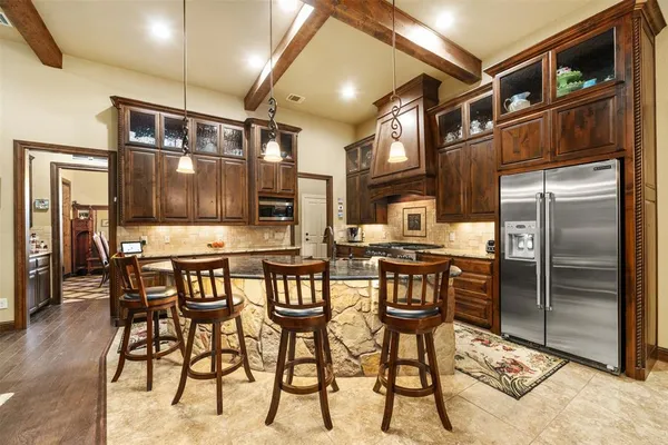 a kitchen with stainless steel appliances kitchen island granite countertop a refrigerator and cabinets