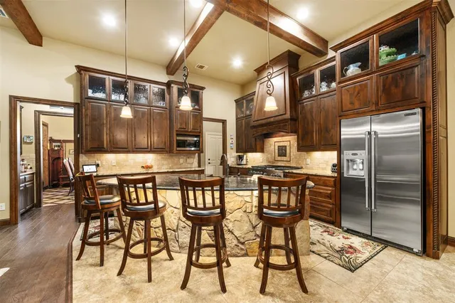 a kitchen with stainless steel appliances kitchen island granite countertop a refrigerator and cabinets