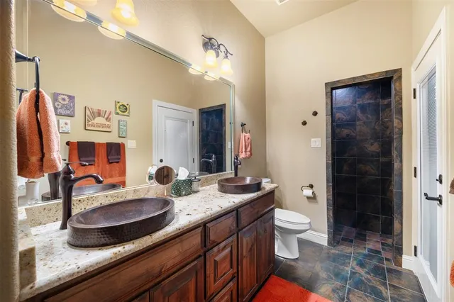 a bathroom with a granite countertop sink a toilet a mirror and shower