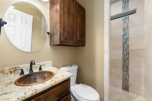 a bathroom with a granite countertop toilet sink and mirror