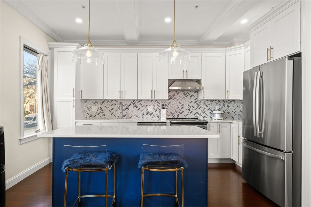 753 East Broadway, Unit 2A Boston, MA 02127 - Photo 2 of 17 a kitchen with kitchen island granite countertop wooden cabinets and refrigerator
