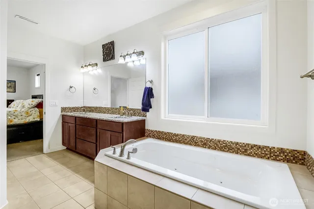 a spacious bathroom with a tub sink and mirror