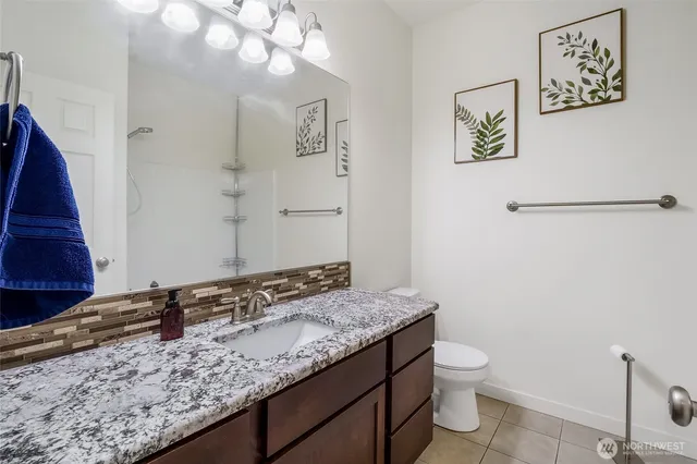 a bathroom with a granite countertop sink a toilet and a mirror