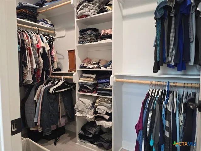 a view of walk in closet with clothes and shoes