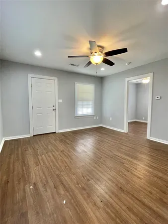 a view of an empty room with a window and wooden floor