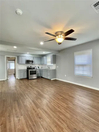 a view of kitchen and livingroom with furniture wooden floor and a ceiling fan