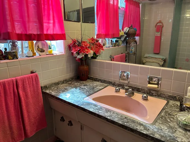 a bathroom with a granite countertop sink a mirror and shower