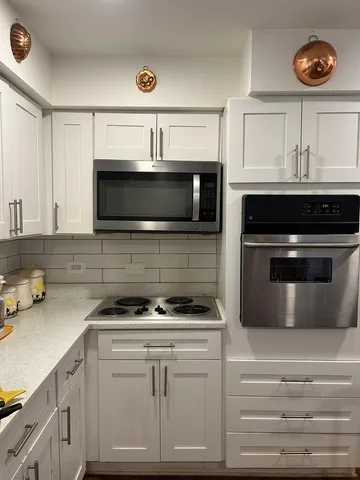 a kitchen with white cabinets and appliances