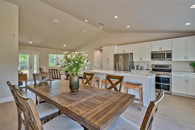 a kitchen with stainless steel appliances a dining table chairs and granite counter tops