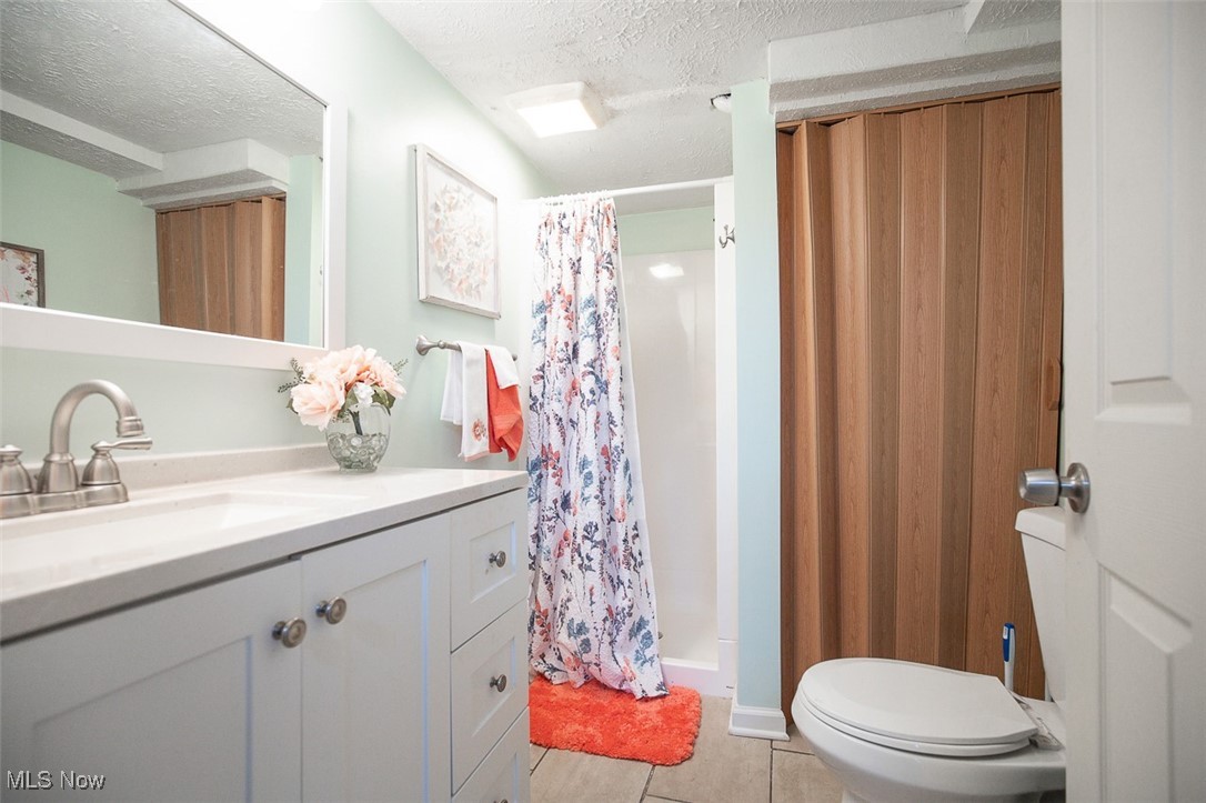15446 Drake Road Strongsville, OH 44136 - Photo 33 of 42 Bathroom with a stall shower, vanity, a textured ceiling, and light tile patterned floors