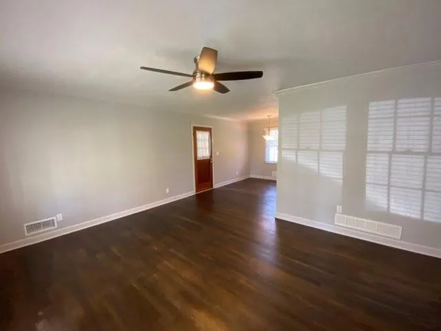 an empty room with wooden floor fan and windows
