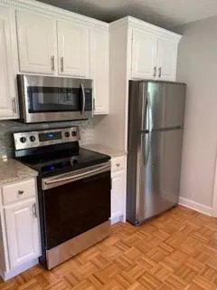 a kitchen with granite countertop a refrigerator stove and microwave