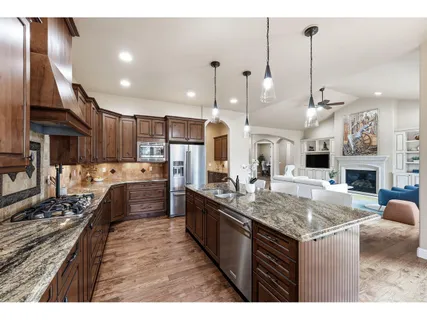 a kitchen with stainless steel appliances granite countertop a sink a stove and a wooden floors