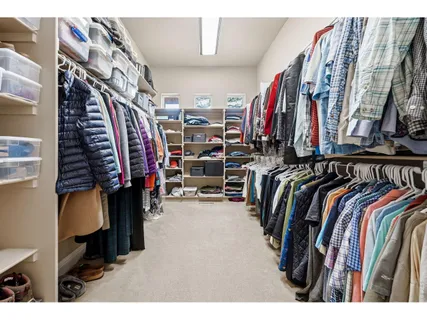 a view of walk in closet with clothes and shoes