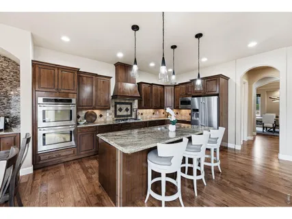 a kitchen with stainless steel appliances kitchen island granite countertop a kitchen island a stove a table and chairs