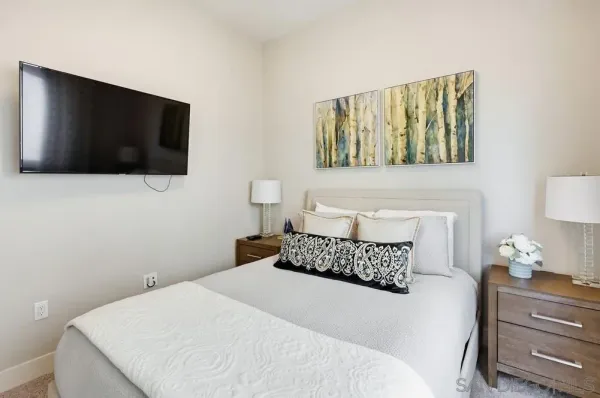 a bedroom with a bed and a flat tv screen on dresser