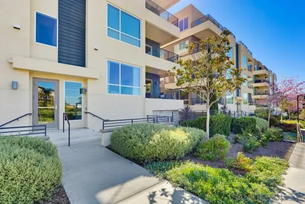 a front view of a multi story residential apartment building with yard and parking
