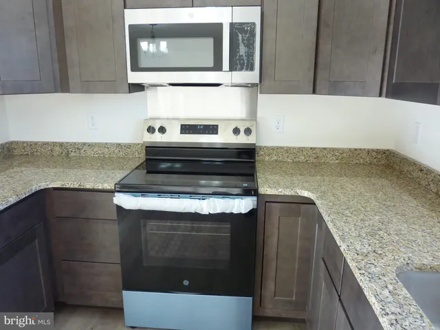 a kitchen with granite countertop a stove and a microwave