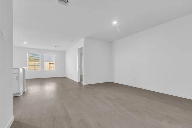 a view of an empty room with window and wooden floor