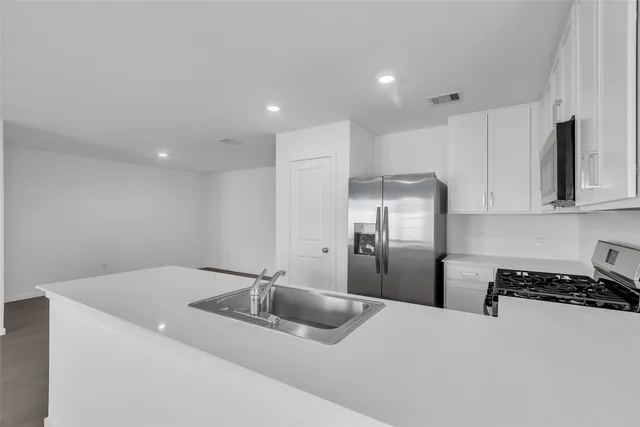 a kitchen with stainless steel appliances granite countertop a refrigerator a sink a stove a microwave and white cabinets