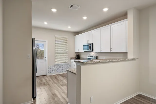 a large kitchen with stainless steel appliances granite countertop a stove a sink and a refrigerator with wooden floors