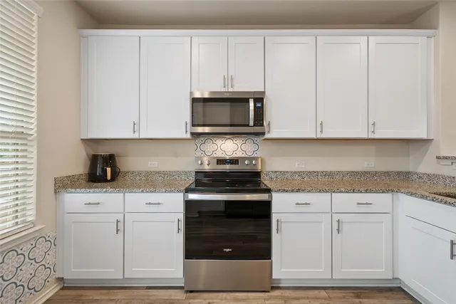 a kitchen with granite countertop white cabinets and stainless steel appliances