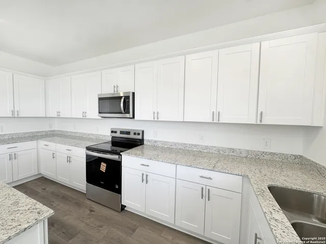 a kitchen with granite countertop white cabinets and stainless steel appliances