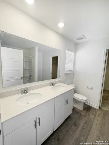 a bathroom with a granite countertop sink a toilet and a mirror