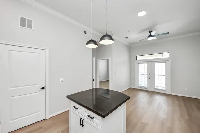 a kitchen with a sink a chandelier stainless steel appliances and wooden floor