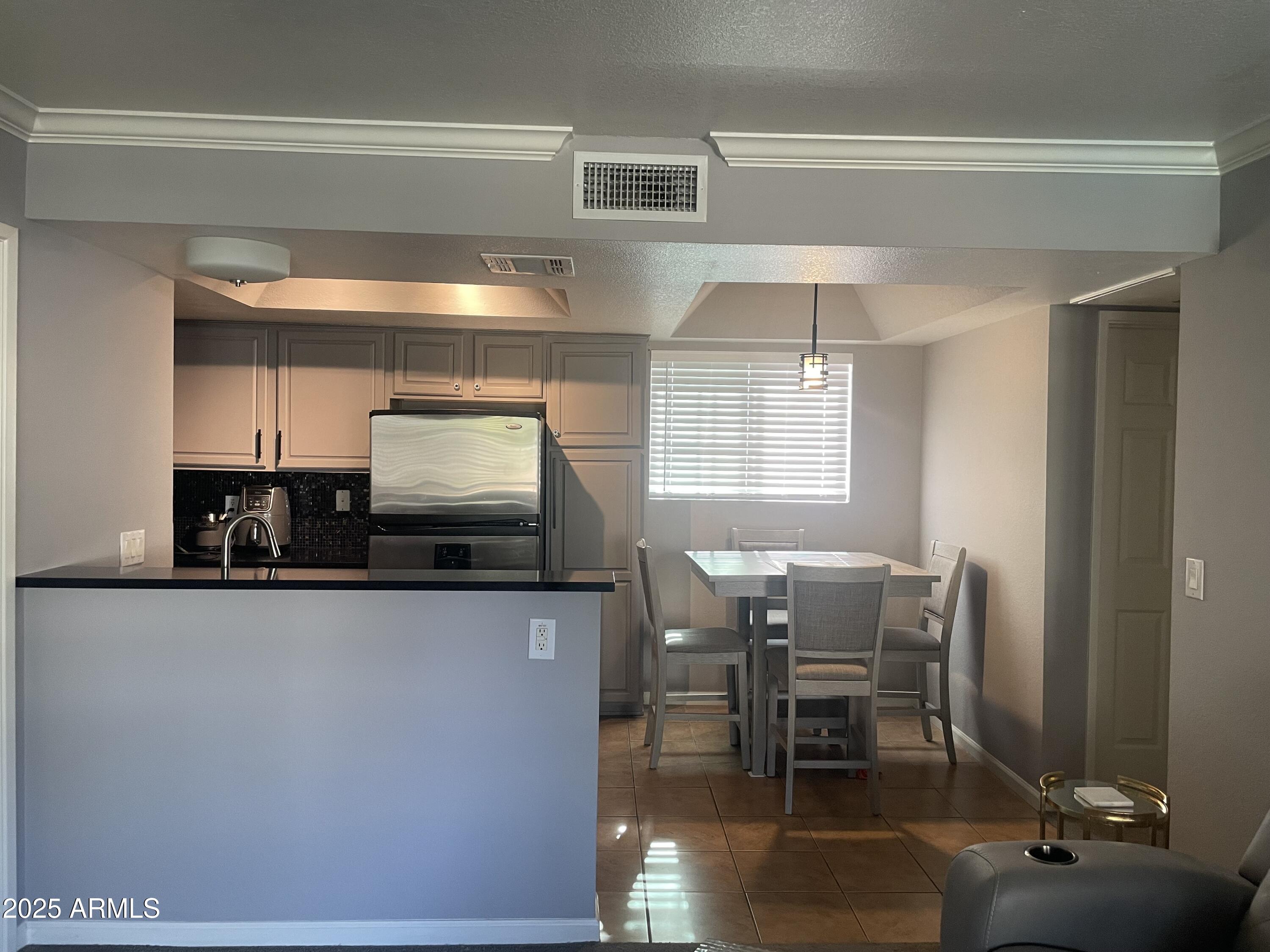 1720 East Thunderbird Road, Unit 2015 Phoenix, AZ 85022 - Photo 13 of 25 a kitchen with stainless steel appliances kitchen island granite countertop a table chairs in it and a window