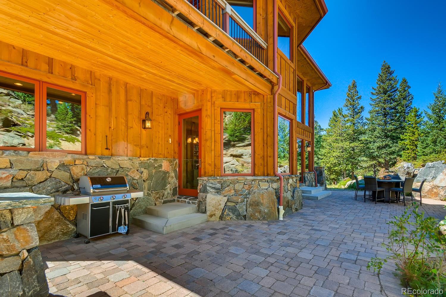 150 Outpost Lane Evergreen, CO 80439 - Photo 11 of 40 a view of a patio with table and chairs potted plants and floor to ceiling window