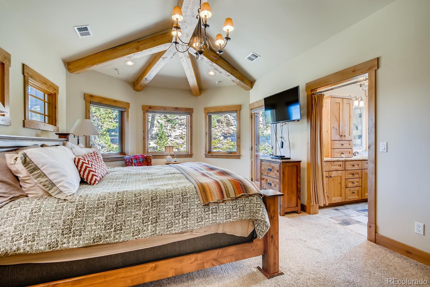 150 Outpost Lane Evergreen, CO 80439 - Photo 20 of 40 a bedroom with a large bed and ceiling fan