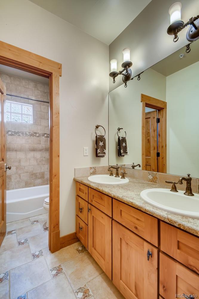 150 Outpost Lane Evergreen, CO 80439 - Photo 28 of 40 a bathroom with a granite countertop sink a mirror and a shower