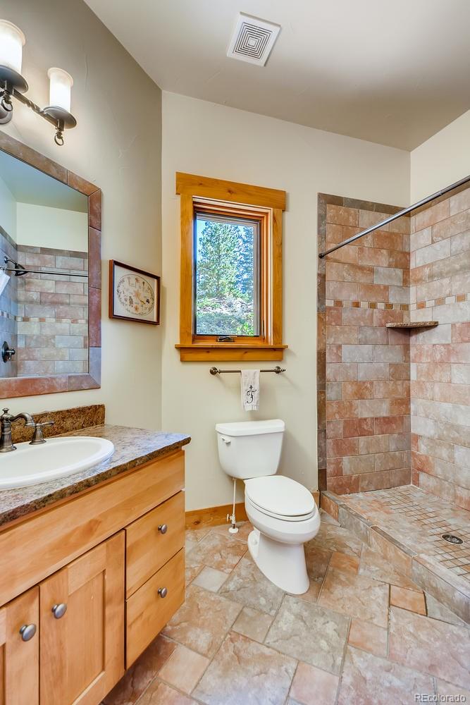 150 Outpost Lane Evergreen, CO 80439 - Photo 31 of 40 a bathroom with a granite countertop toilet a sink and a shower