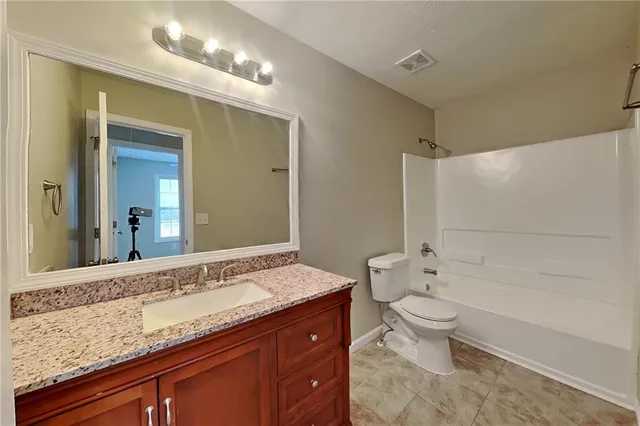 a bathroom with a granite countertop sink a toilet and bathtub