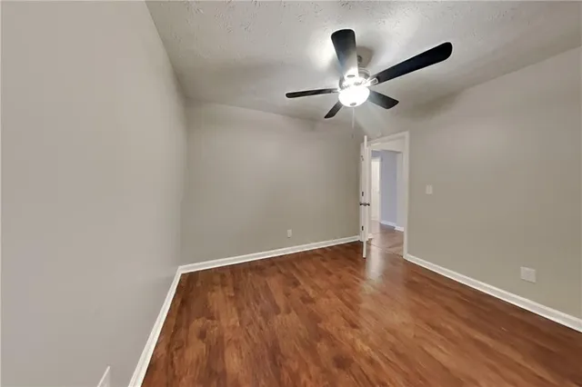 an empty room with wooden floor chandelier fan and closet