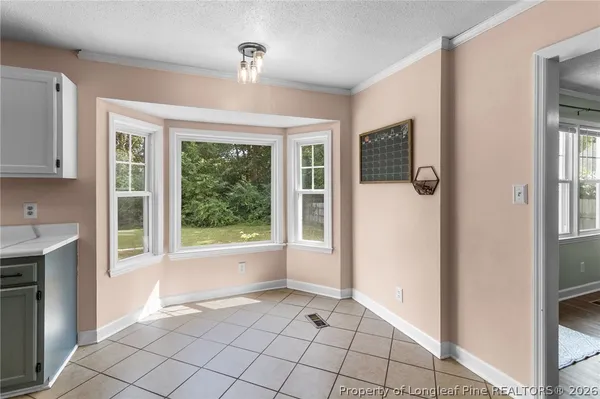a view of an empty room with window and chandelier
