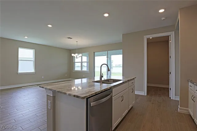 a kitchen with granite countertop a sink and white cabinets with wooden floor