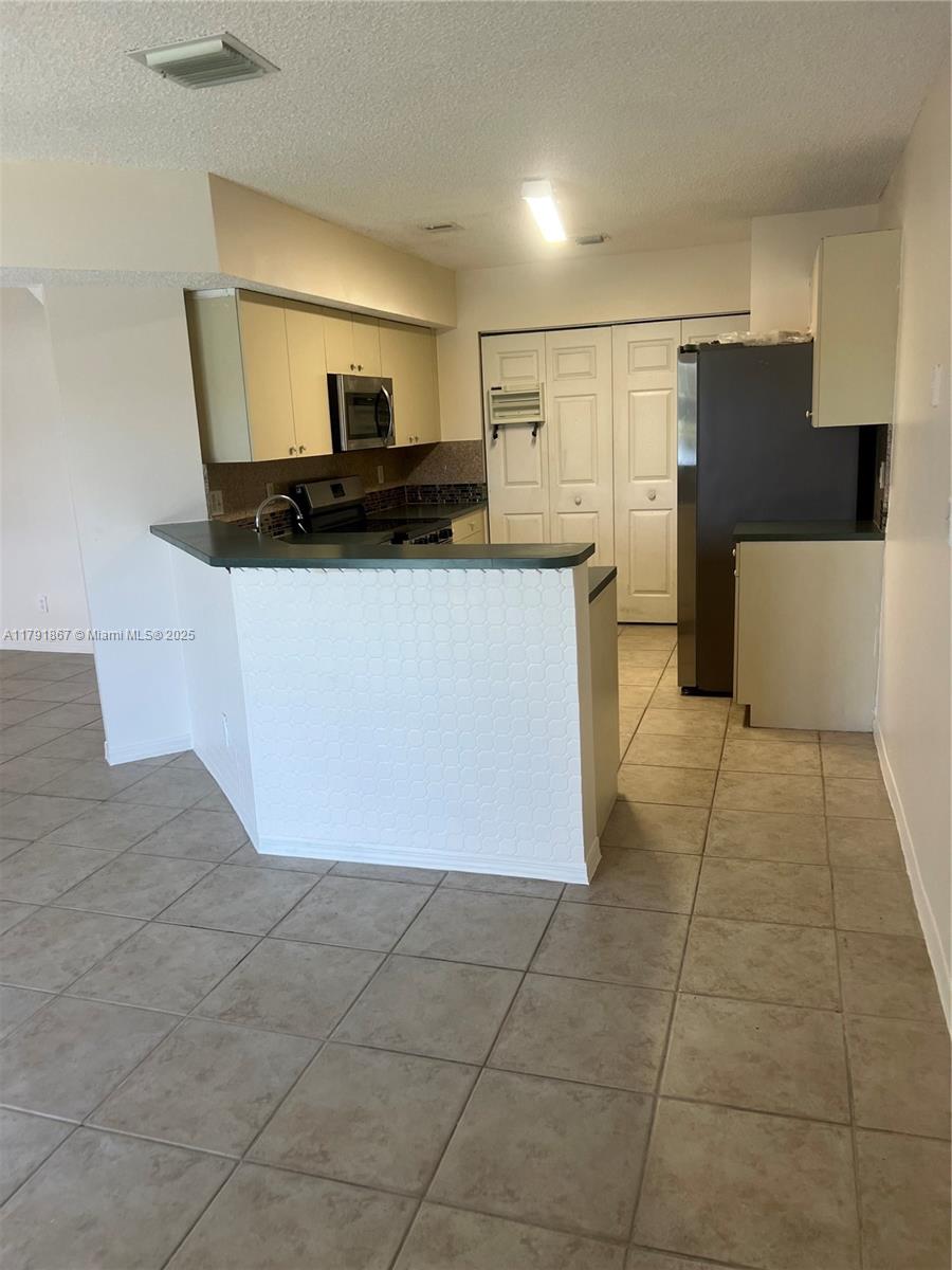 5357 Southwest 125th Avenue Miramar, FL 33027 - Photo 11 of 39 a view of a refrigerator in kitchen and an empty room