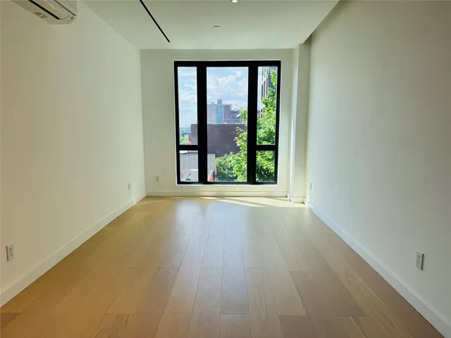an empty room with wooden floor and outdoor view