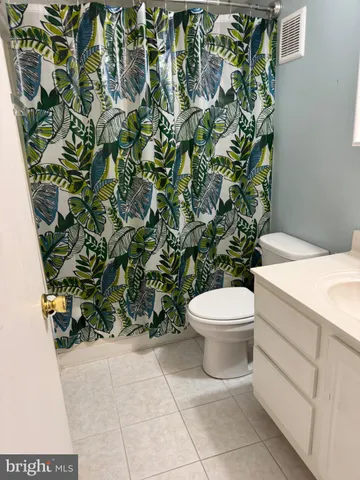 a white toilet sitting next to a white sink and vanity