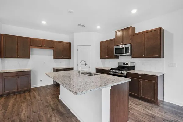 a kitchen with stainless steel appliances granite countertop a sink a stove a microwave a counter space and cabinets