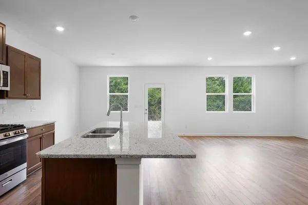 a view of kitchen with microwave a stove and wooden floor