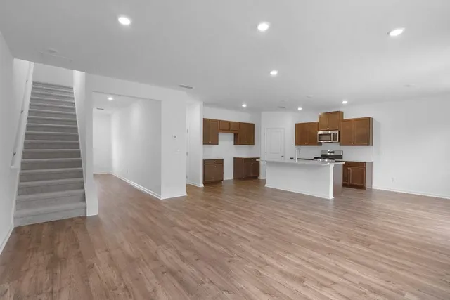 a view of kitchen with microwave a refrigerator and a stove top oven